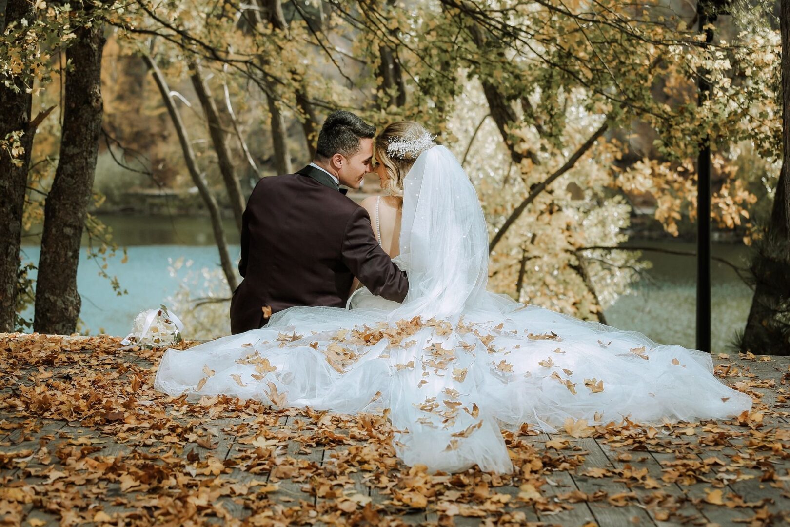 A man and woman sitting on the ground in front of trees.